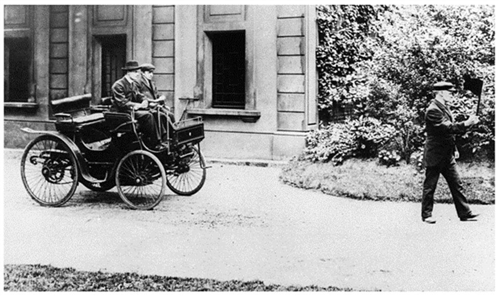A black and white photo of men driving a carriage

Description automatically generated